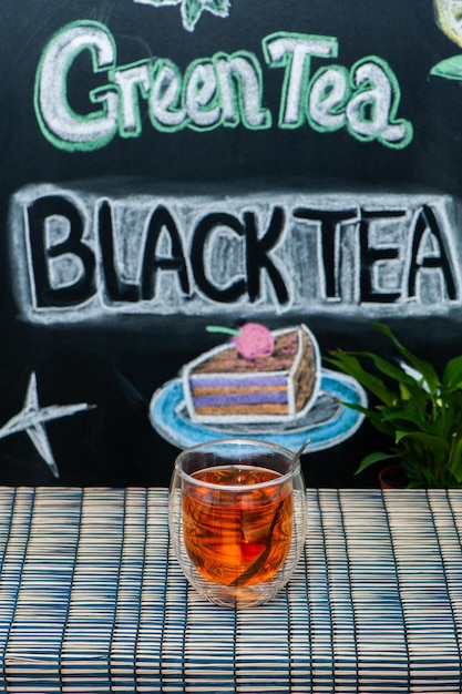 Foto taza con té negro en el fondo de graffiti con inscripciones y dibujos en una pizarra