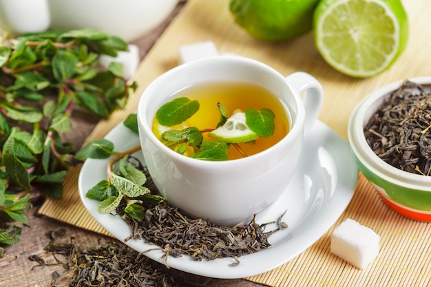 Taza de té negro con hojas de menta en una mesa de madera