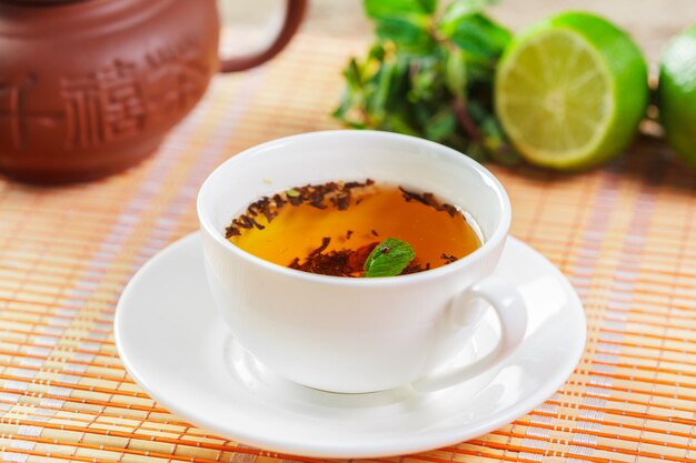 Taza de té negro con hojas de menta en una mesa de madera