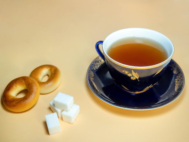 Una taza de té negro con terrones de azúcar y sushki