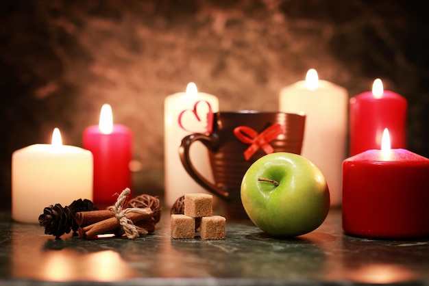 Taza de té de noche con vela y manzana.