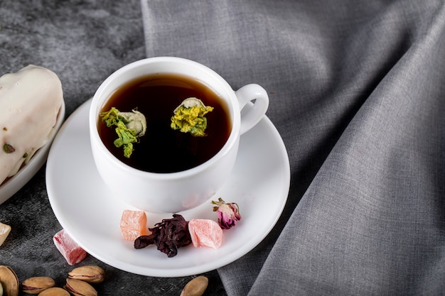 Una taza de té con nueces, lokum turco y flores