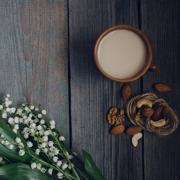 Una taza de té, nueces, ramo de lirios sobre un fondo de madera