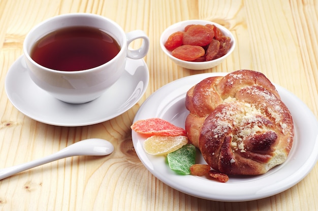 Taza de té y pan con frutos secos sobre mesa de madera