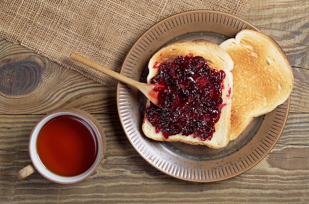 Taza de té y pan tostado con mermelada en una mesa de madera