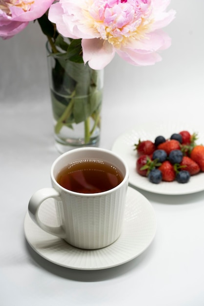 Taza de té, peonía y bayas.