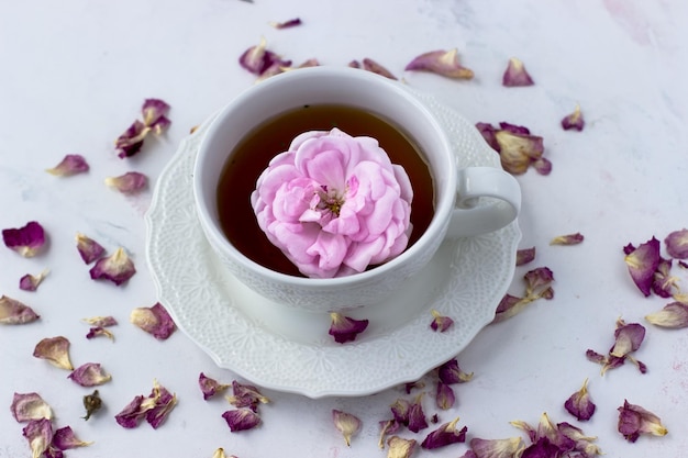 Una taza de té y pétalos de rosa de té sobre una mesa de mármol blanco Ritual del té