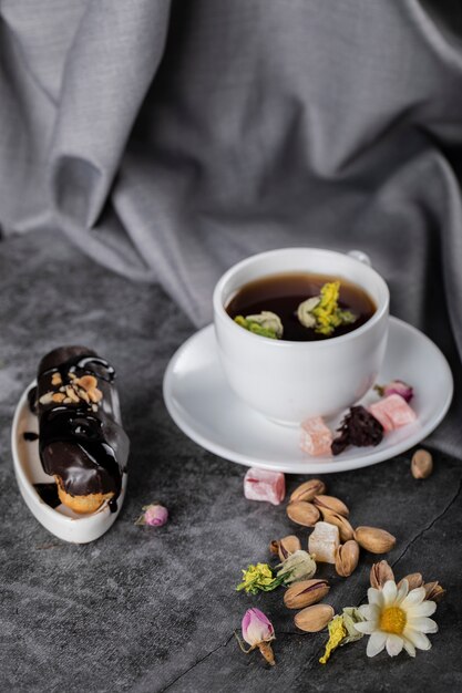 Una taza de té con pistachos y pastel de chocolate decorado con flores.