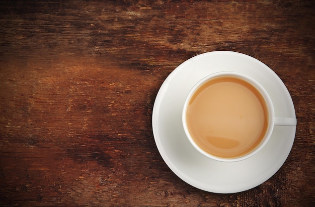 Taza de té de porcelana con leche sobre fondo de madera