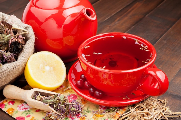 Taza de té rojo y tetera hierbas curativas y limón.