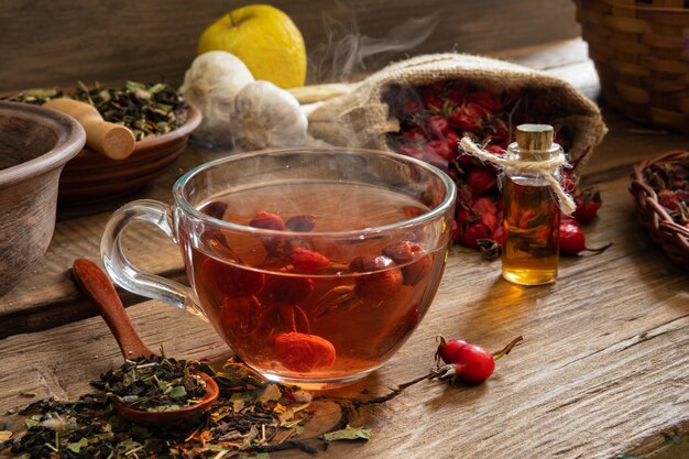 Una taza de té de rosa silvestre útil para la salud sobre un fondo de madera. Fruta de escaramujo en una bolsa de lona.