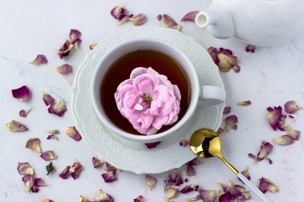 Una taza de té con una rosa de té sobre un fondo de mármol blanco Buenos días Vista superior