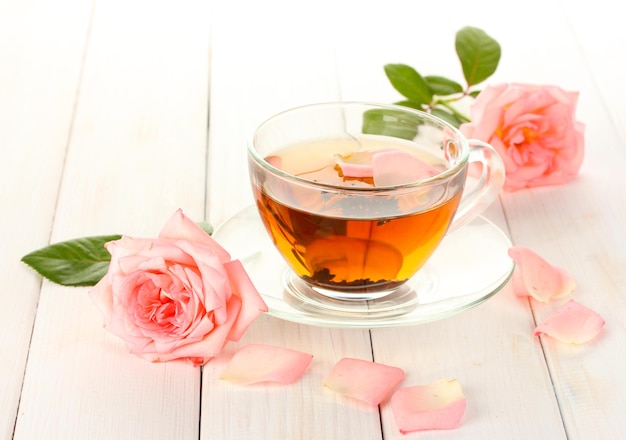 Foto taza de té con rosas en la mesa de madera blanca