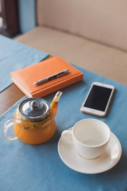 Una taza de té saludable de hierbas vitamínicas de espino amarillo de naranja y bayas en una tetera de vidrio