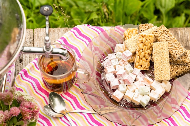 Una taza de té y un samovar en una mesa de madera con dulces.