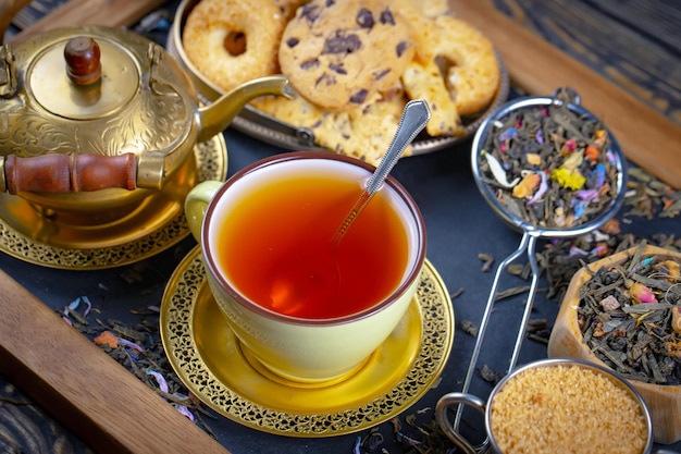 Una taza de té se sienta en una bandeja con té y galletas.