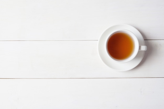 Una taza de té sobre fondo blanco de madera.