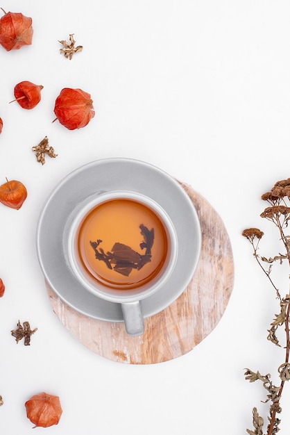 Una taza de té sobre un fondo blanco en un puesto de madera con plantas de otoño