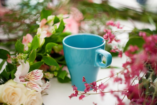 Taza de té sobre la mesa, relájate. Taller de floristería, mesa con flores, naturaleza muerta. Enfoque suave