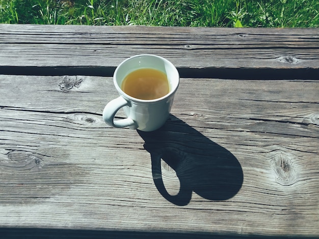 taza de té con una sombra en la terraza de madera