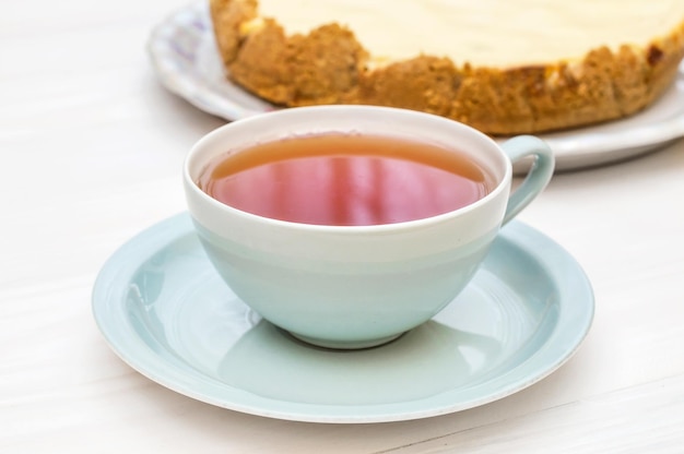 Taza de té con tarta de queso en plato