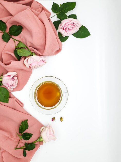 Una taza de té y un tazón de té con rosas rosas sobre un fondo blanco.