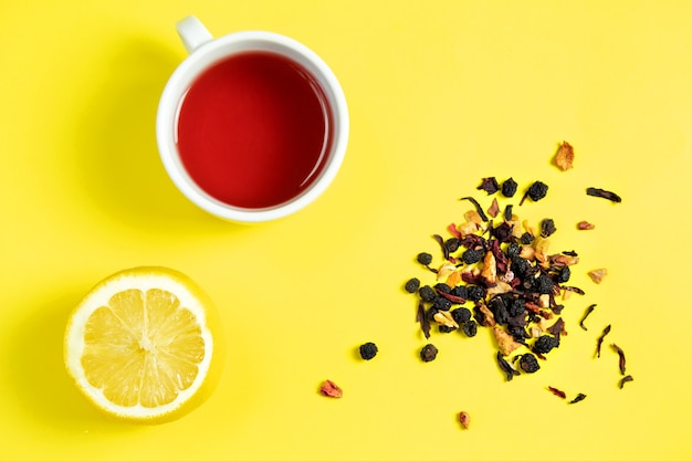 Taza de té, té de frutas con limón y una diapositiva de limón en amarillo, vista superior