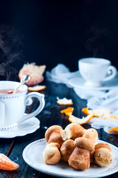 Taza de té con té y galletas ángel, mandarina sobre una mesa negra