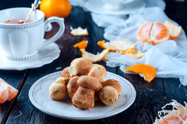 Taza de té con té y galletas ángel, mandarina sobre una mesa negra