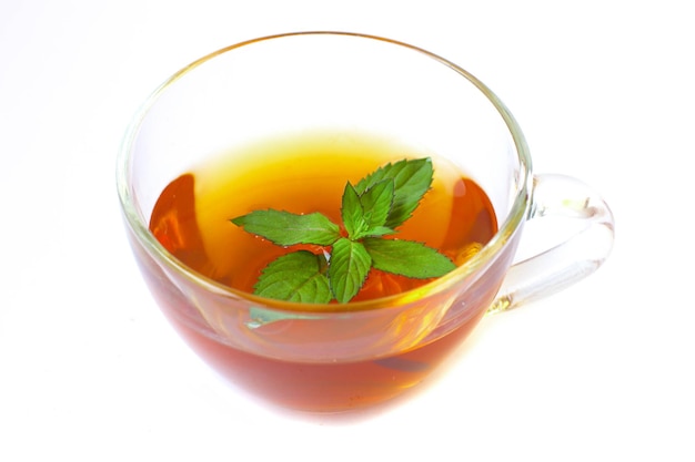 Taza de té transparente con hojas de menta aislado sobre fondo blanco.