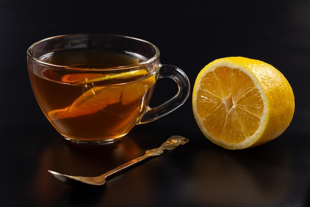 Taza de té y trozos de limón sobre fondo negro