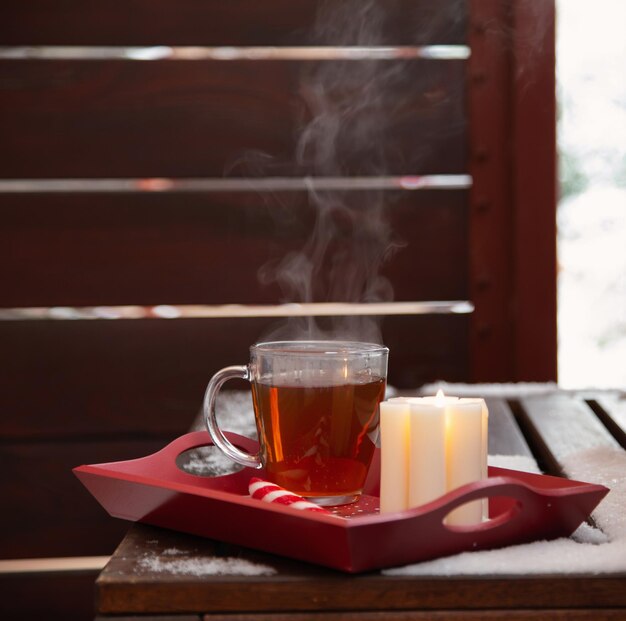 Foto taza de té con una vela encendida en la nieve en el balcón en invierno