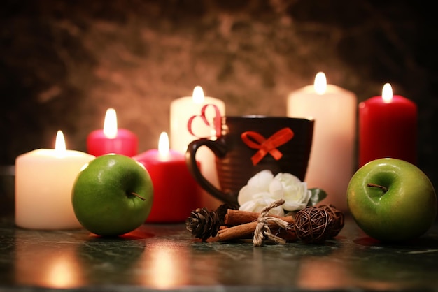 taza de té con vela y manzana por la noche