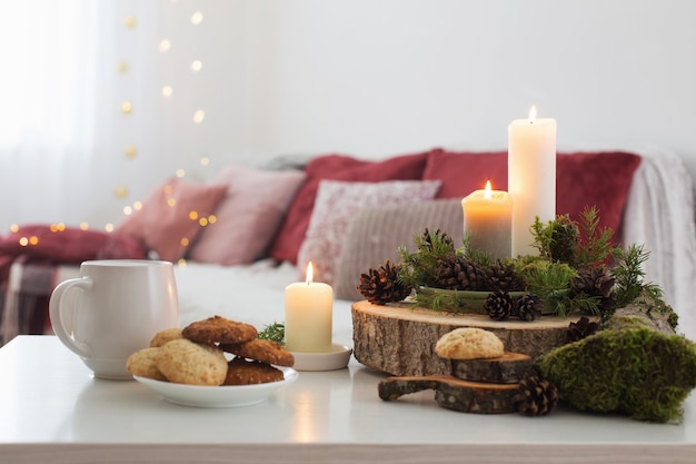 Taza de té con velas encendidas sobre mesa blanca