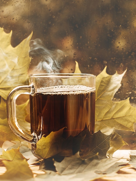 Taza de té en una ventana lluviosa hoja del día del estado de ánimo de otoño