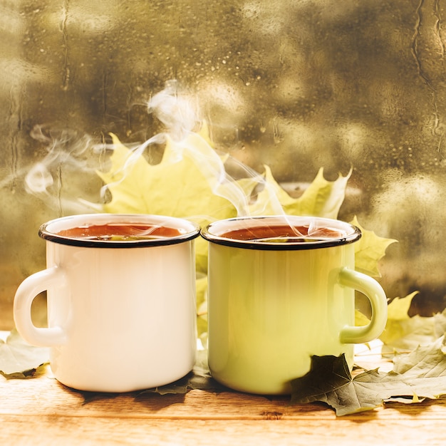 Taza de té en una ventana lluviosa hoja del día del estado de ánimo de otoño