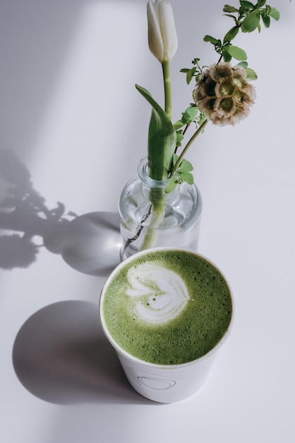Una taza de té verde con una flor en el centro.