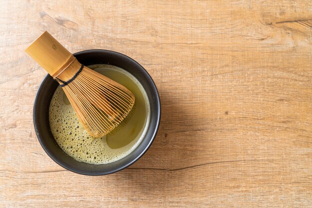 taza de té verde matcha caliente con polvo de té verde y batidor