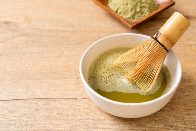 taza de té verde matcha caliente con polvo de té verde y batidor