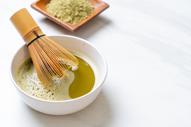 taza de té verde matcha caliente con polvo de té verde y batidor