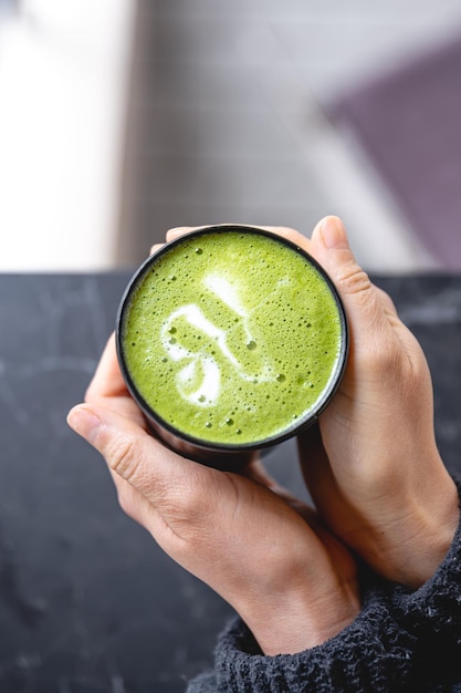 Taza de té verde matcha en vista superior de mano de mujer