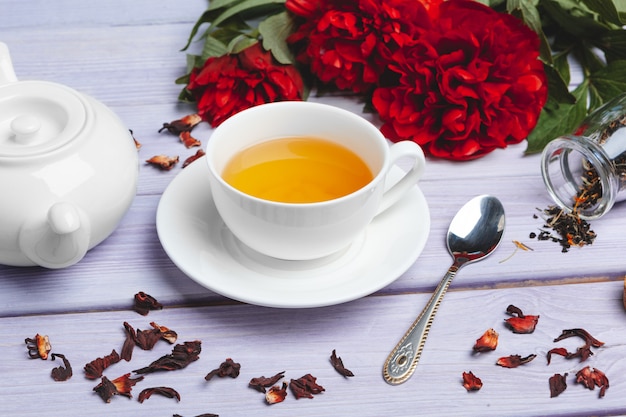 Taza de té verde en la mesa con flores de peonía fresca