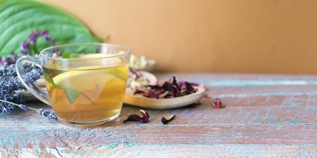 Taza de té verde con pétalos secos de menta y limón de plantas útiles en una mesa de madera