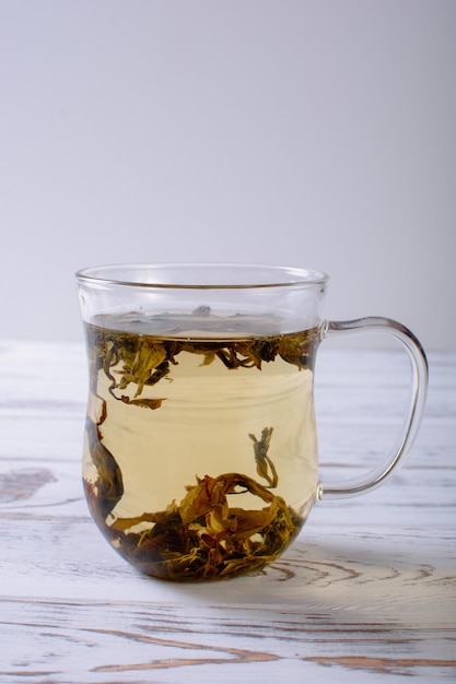 Taza con té verde y tetera sobre fondo de mesa de madera blanca sobre luz