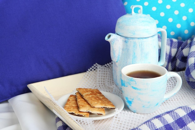 Taza y tetera con galletas en la cama de cerca