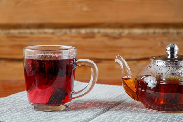 Taza y tetera de té de hibisco sobre la mesa en una servilleta Foto horizontal