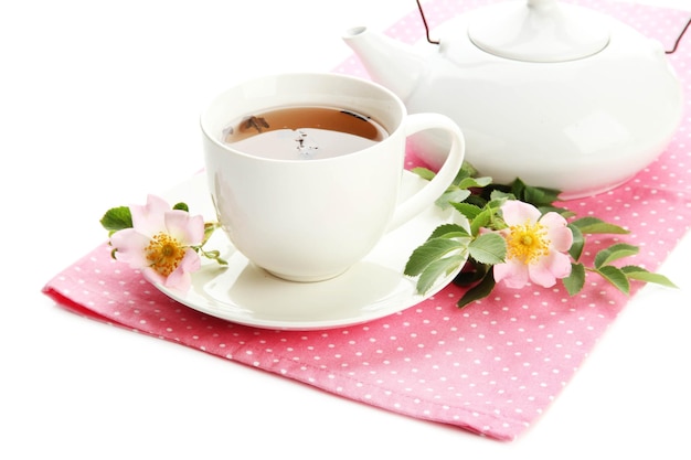 Taza y tetera de té de hierbas con flores de rosa mosqueta aisladas en blanco