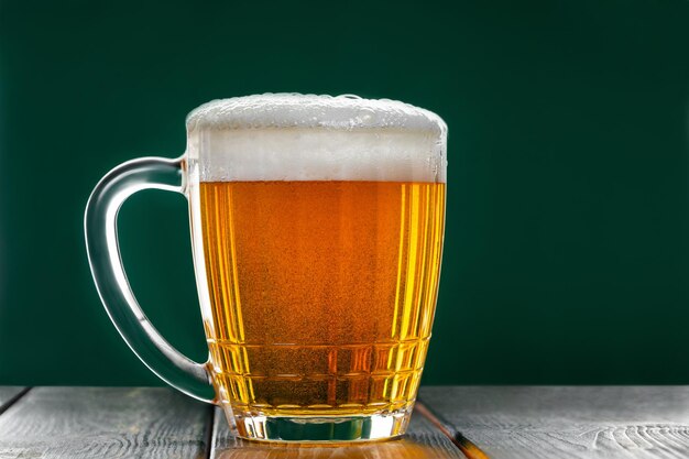 Foto taza con tradicional cerveza irlandesa pálida sobre un fondo verde oscuro burbujas en un vaso de cerveza