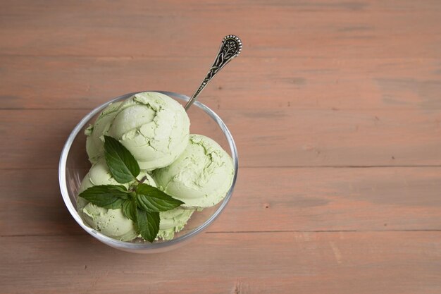 Taza transparente con bolas de helado de té verde matcha sobre fondo de madera