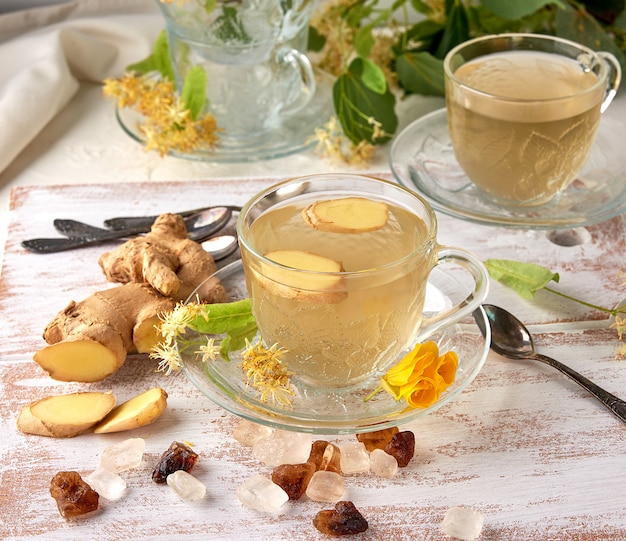 Taza transparente de té de tilo de hierbas y trozos de jengibre.